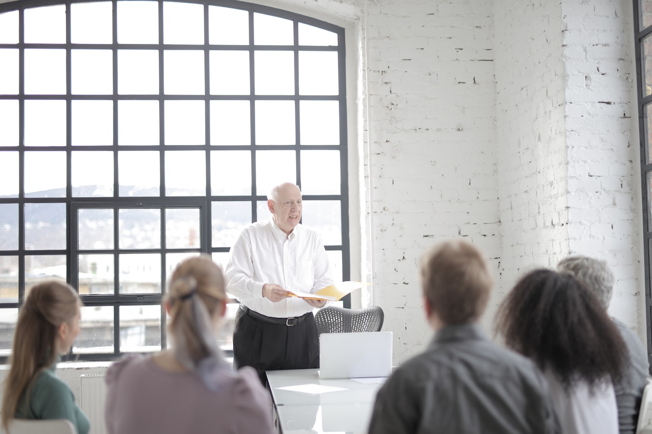 Colleagues listening to executive at meeting in office boardroom